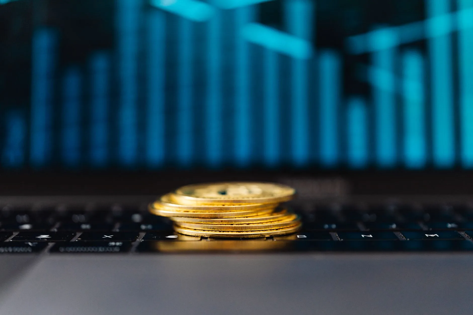 Stack of gold coins on a laptop keyboard with a rising graph, symbolizing financial growth. 币圈内容说明图