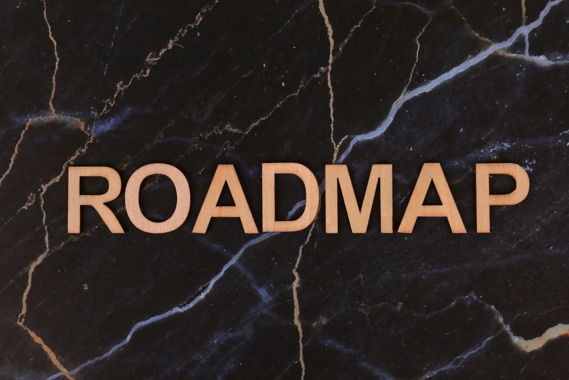 Wooden letters spelling ROADMAP on a dark marble surface, ideal for business presentations. 说明图
