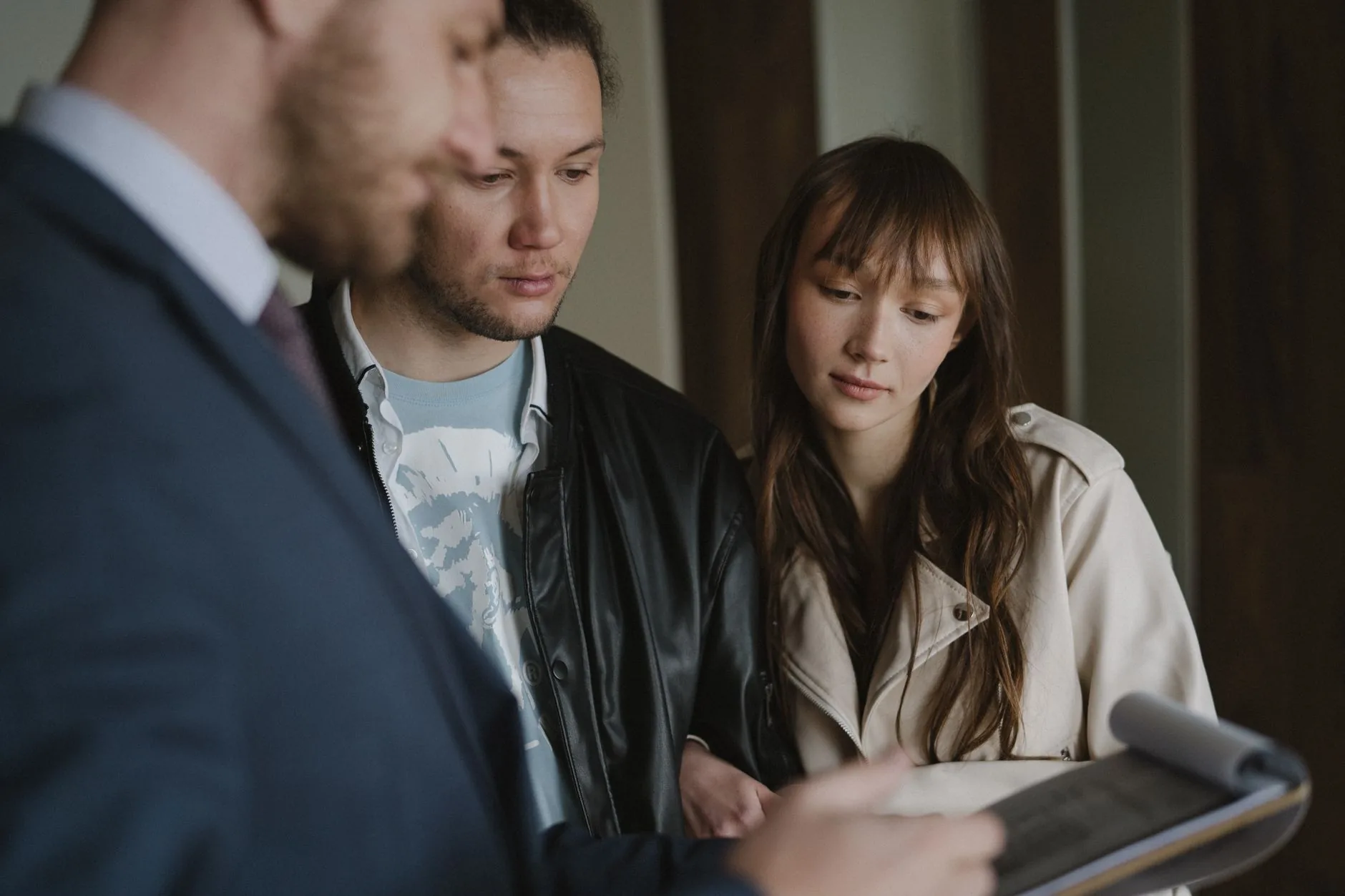 A couple discusses home buying details with a realtor inside a modern apartment. 说明图